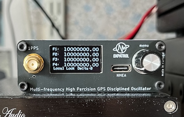 The front panel of a DX Patrol GPSDO v.3 showing 4 lines F1 to F4, each set to 10000000.00.