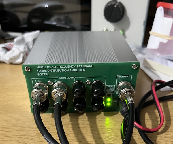 A BG7TBL 10MHz distribution amplifier with 9 BNC connectors and a green front panel.